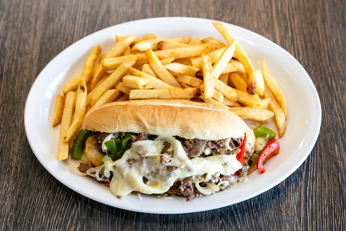 Cheesesteak sandwich with fries on a white plate