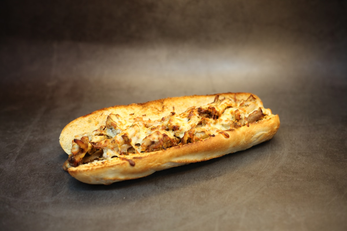 Toasted cheesesteak sandwich on a dark grill surface